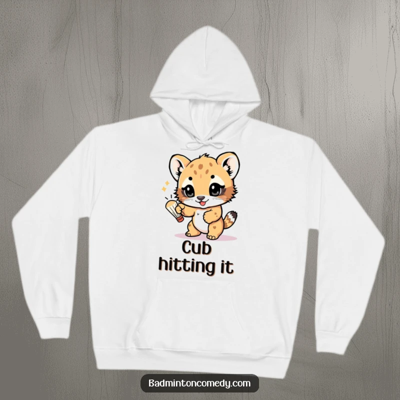 Funny hoodie depicting a joyful bear cub batting a shuttlecock with its paw, eyes sparkling with excitement and a love for games.